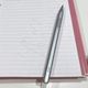 The MSI Pen 2 stylus sitting on a paper notebook with a page covered in scribbles.